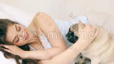 女人在床上抱着小狗。 视频片段，轻松阳光的早晨时刻。 LO家族